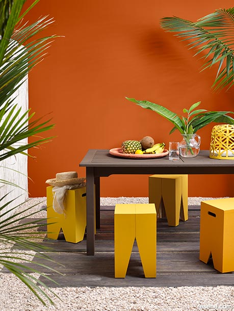 A burnt orange outdoor dining area with yellow stools