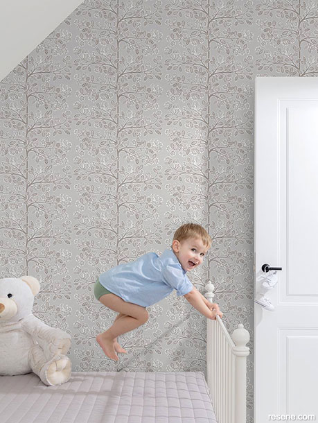 A kids bedroom with neutral wallpaper 